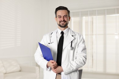 Portrait of smiling cardiologist with clipboard in clinic