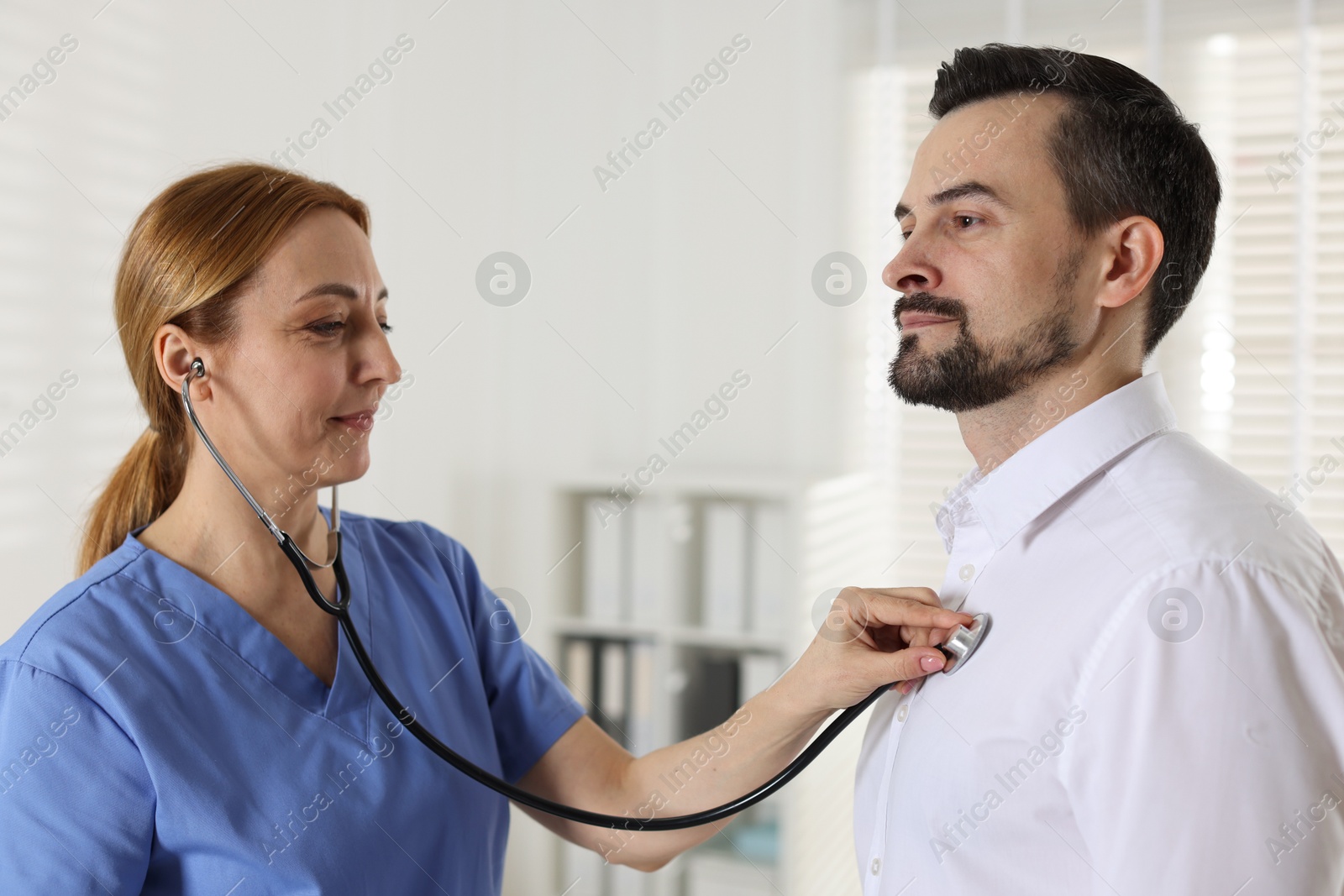 Photo of Cardiologist with stethoscope listening patient's heartbeat in hospital