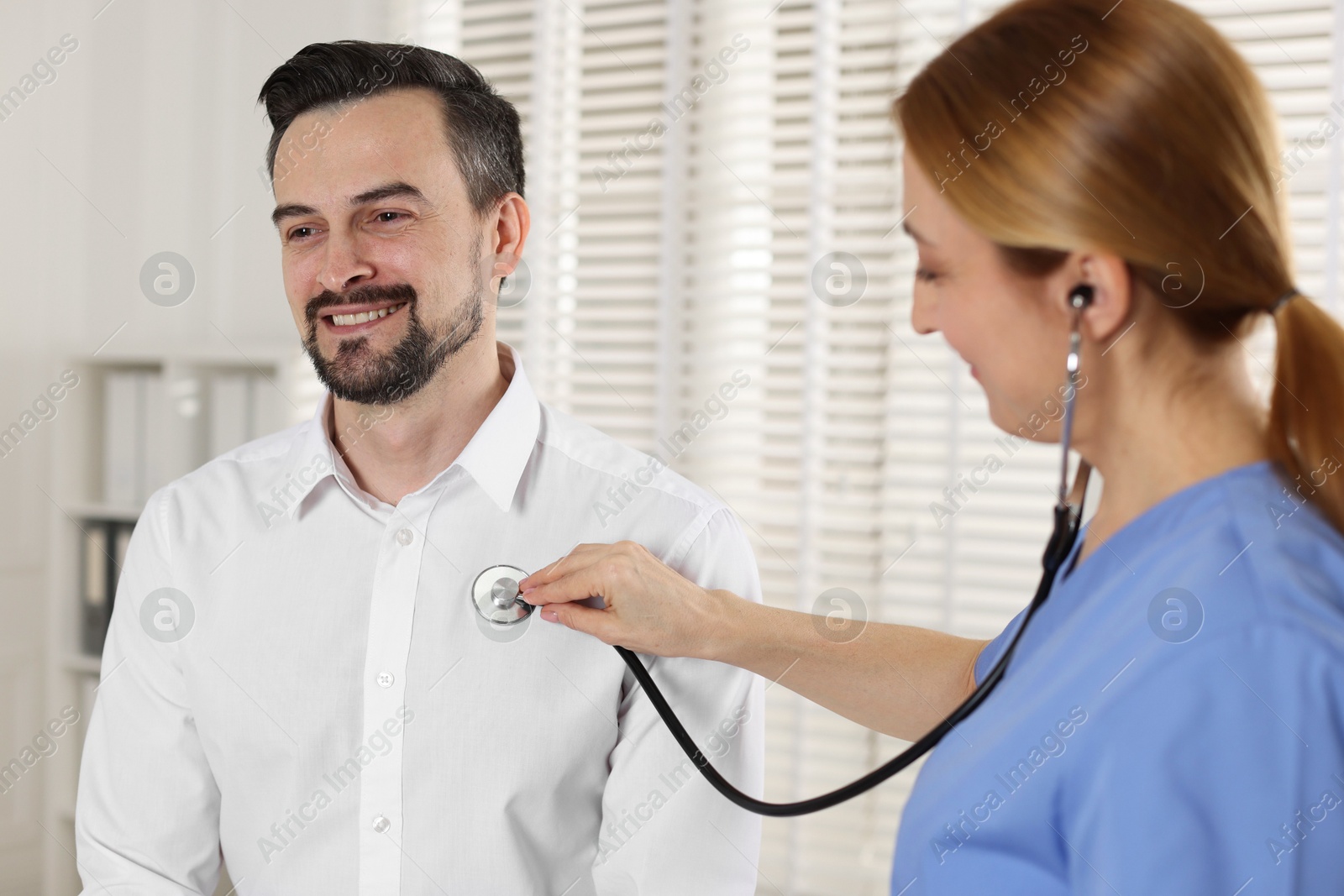 Photo of Cardiologist with stethoscope listening patient's heartbeat in hospital