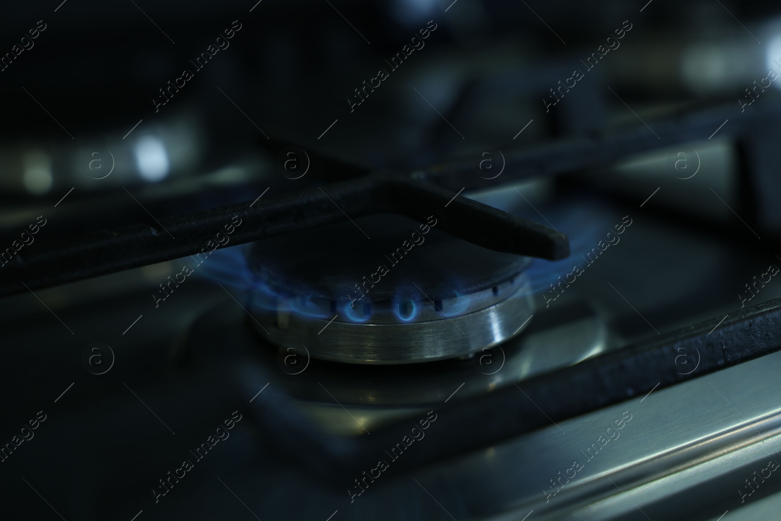 Photo of Gas burner with blue flame on stove, closeup