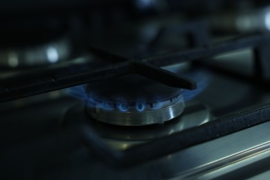 Photo of Gas burner with blue flame on stove, closeup