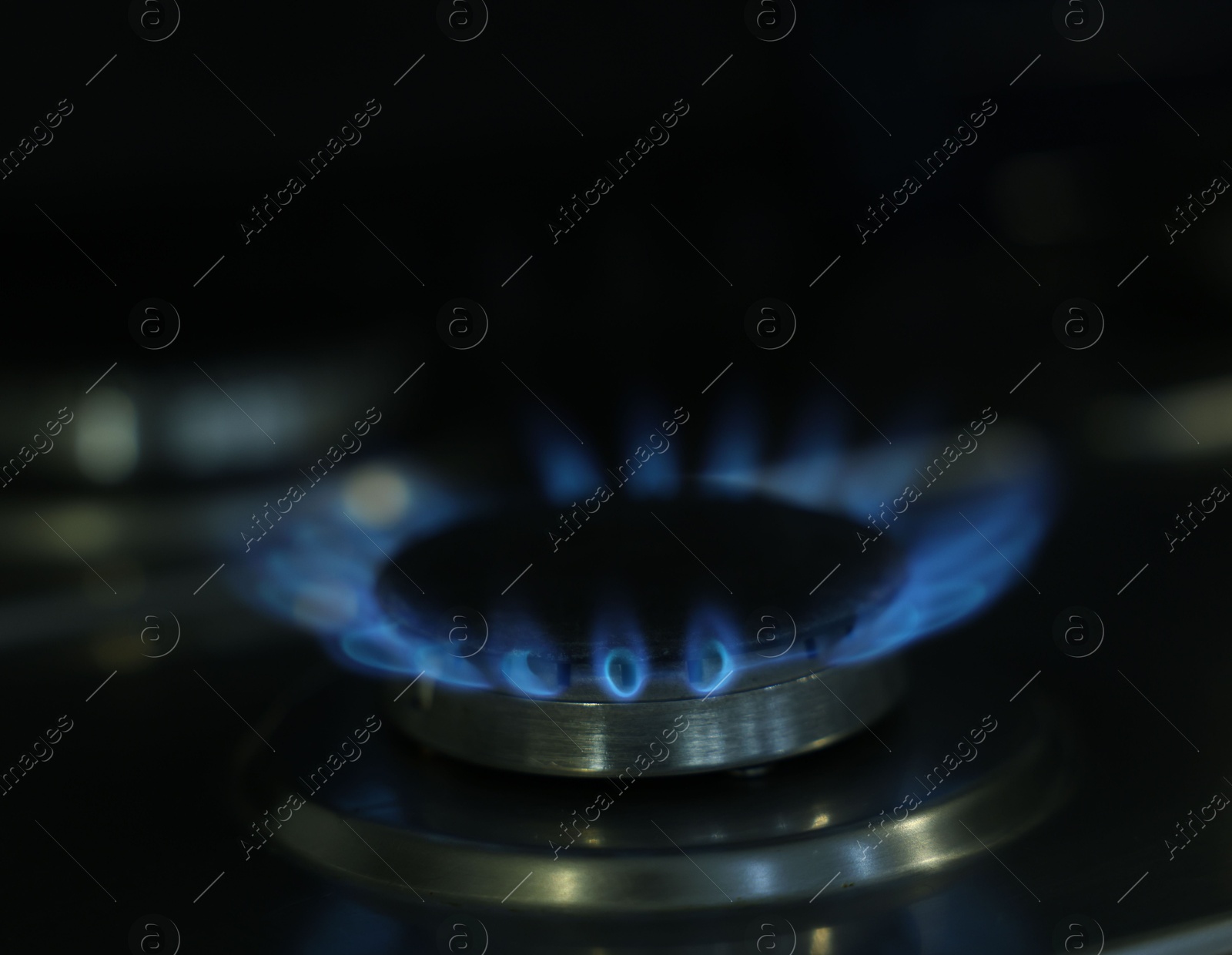 Photo of Gas burner with blue flame on stove, closeup