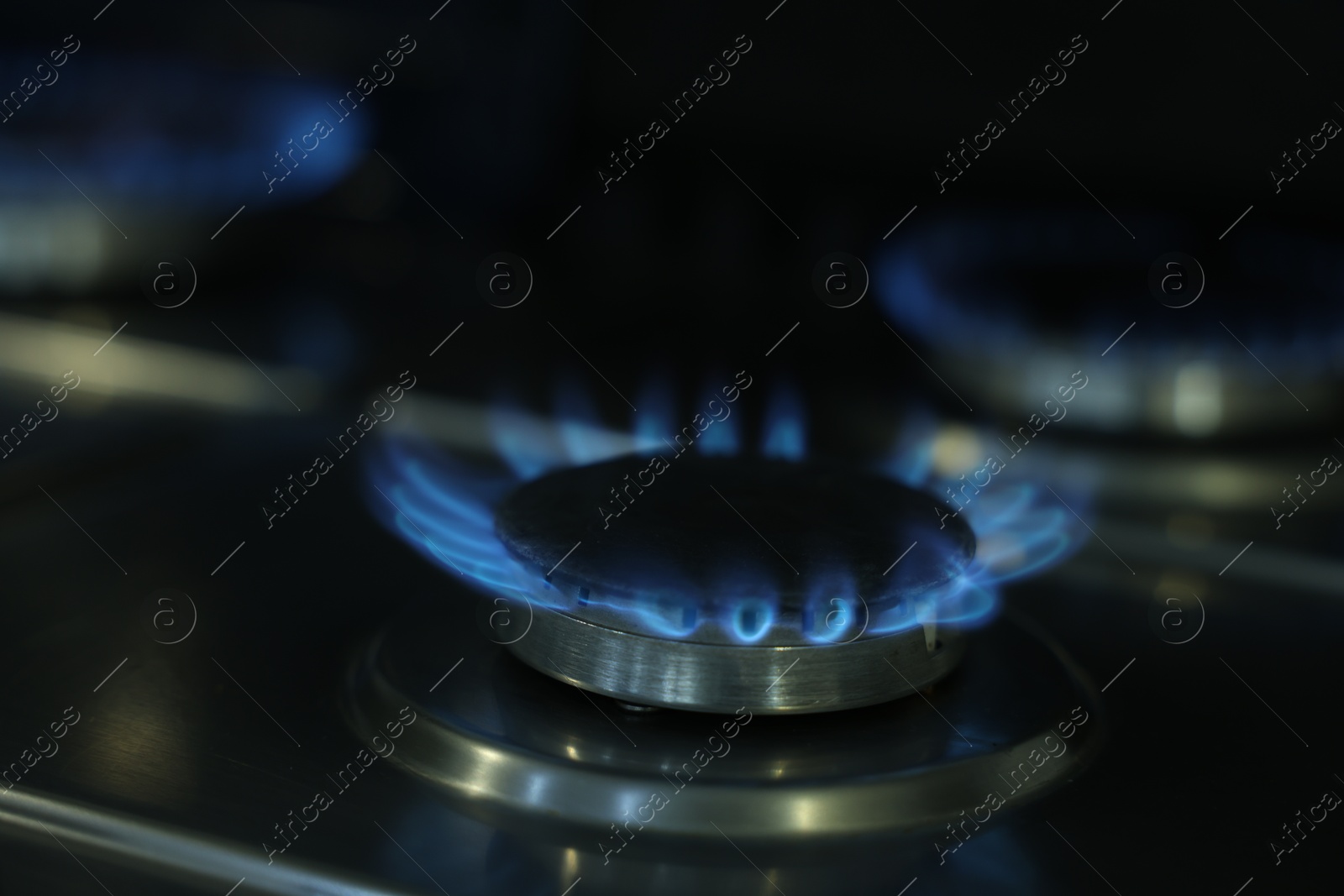 Photo of Gas burners with blue flame on stove, closeup