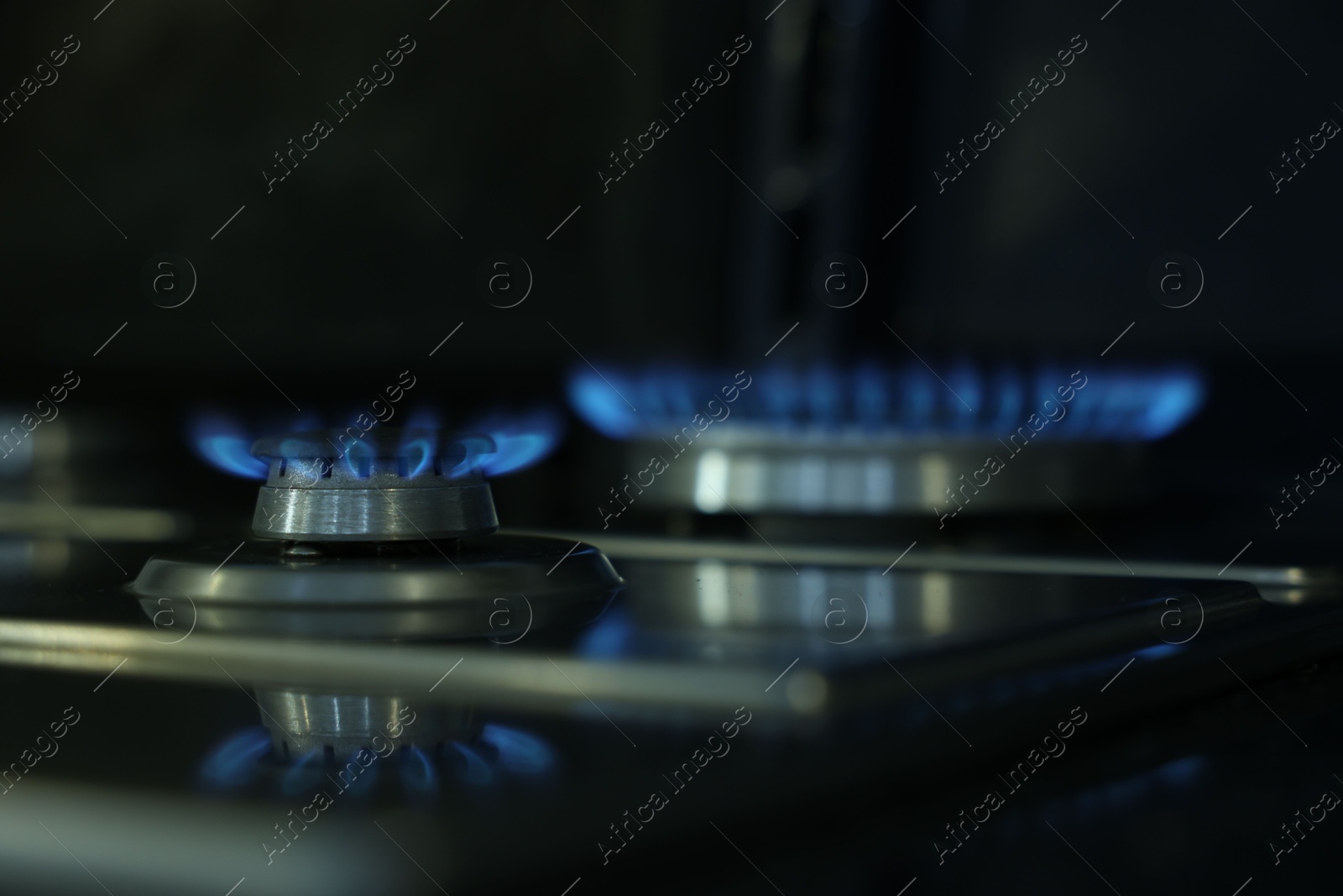 Photo of Gas burners with blue flame on stove, closeup