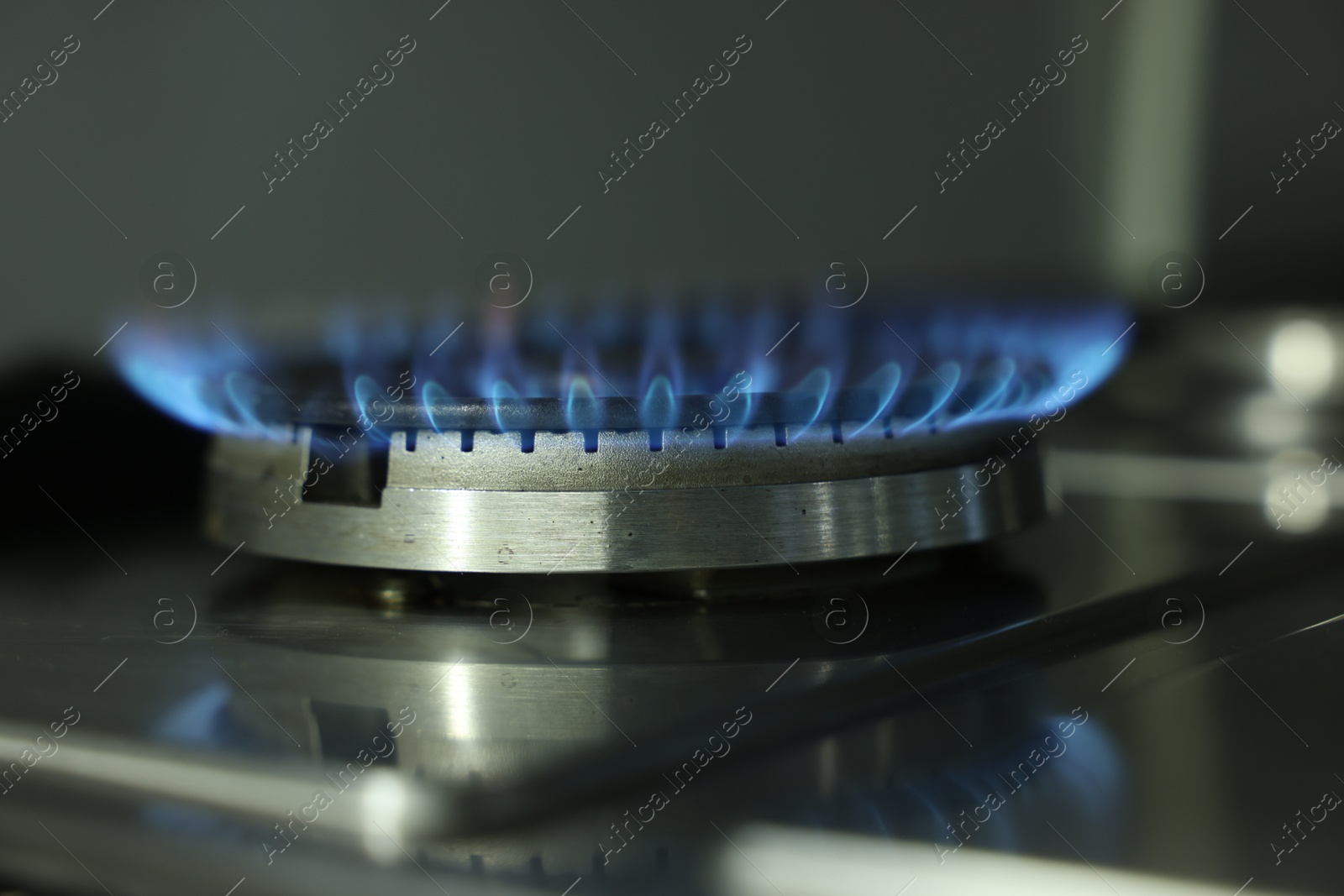 Photo of Gas burner with blue flame on stove, closeup