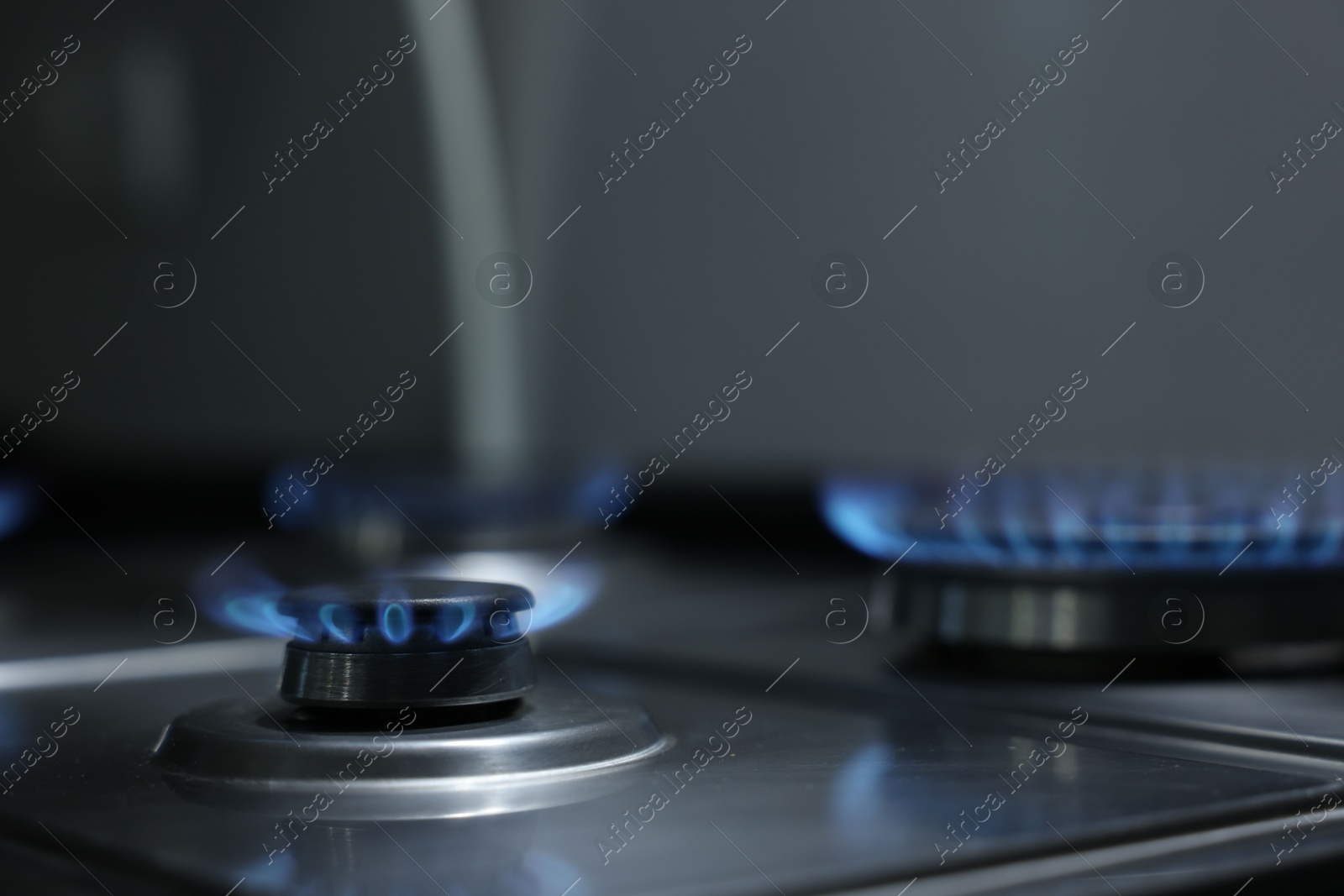 Photo of Gas burners with blue flame on stove, closeup