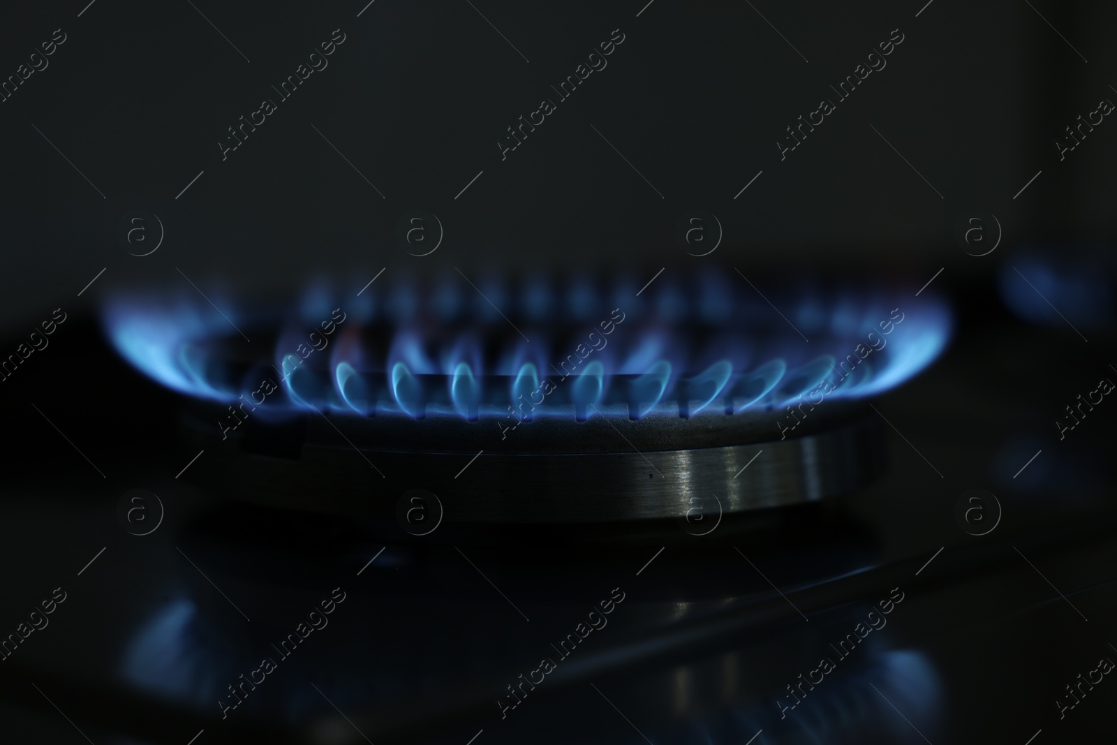 Photo of Gas burner with blue flame on stove, closeup