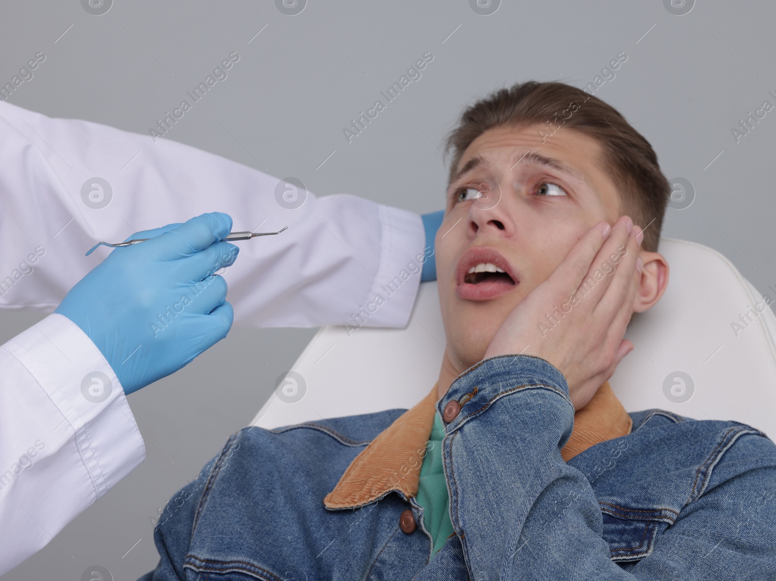 Photo of Scared man having appointment with dentist on grey background