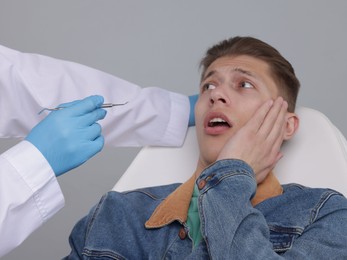 Photo of Scared man having appointment with dentist on grey background