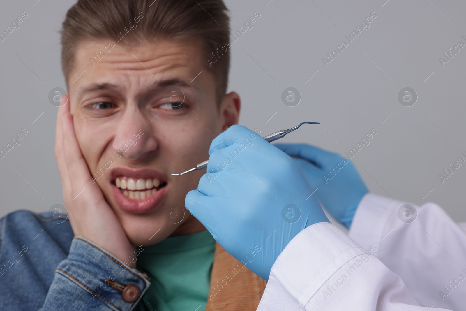 Photo of Scared man having appointment with dentist on grey background