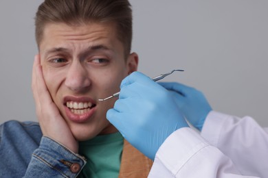 Photo of Scared man having appointment with dentist on grey background