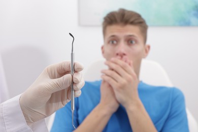 Scared man having appointment with dentist in clinic, selective focus