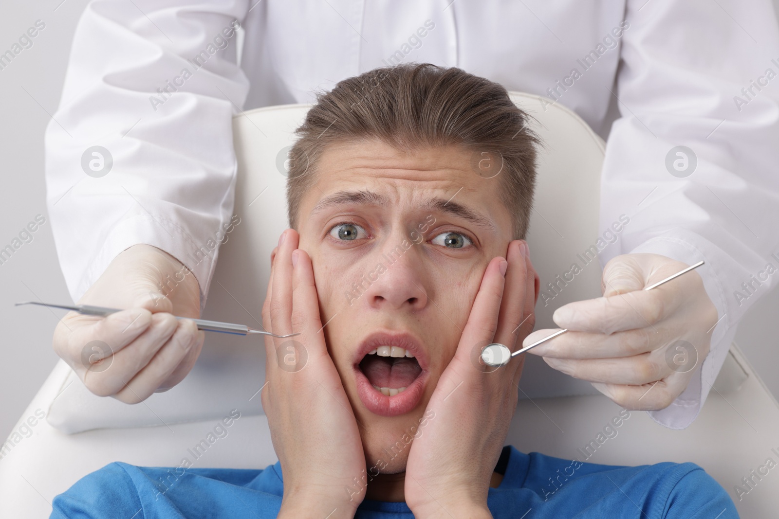 Photo of Scared man having appointment with dentist on grey background