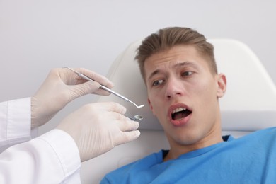 Photo of Scared man having appointment with dentist on grey background