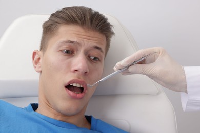 Photo of Scared man having appointment with dentist on grey background