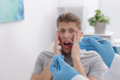 Photo of Scared man having appointment with dentist in clinic, selective focus. Space for text