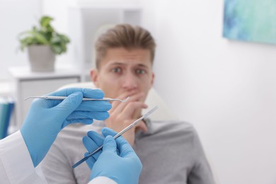 Photo of Scared man having appointment with dentist in clinic, selective focus. Space for text