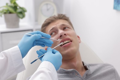 Photo of Scared man having appointment with dentist in clinic, selective focus