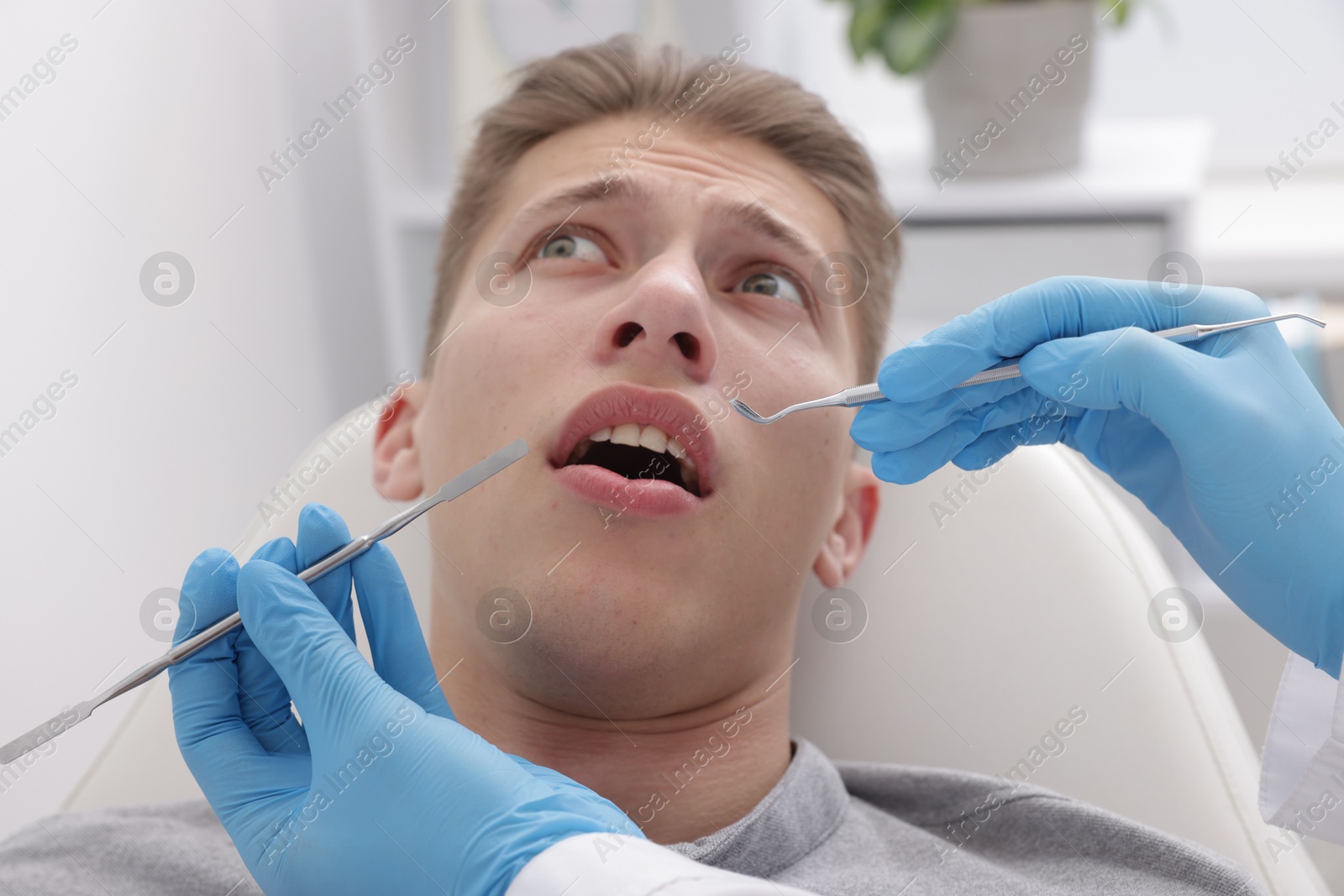 Photo of Scared man having appointment with dentist in clinic