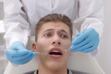 Photo of Scared man having appointment with dentist in clinic