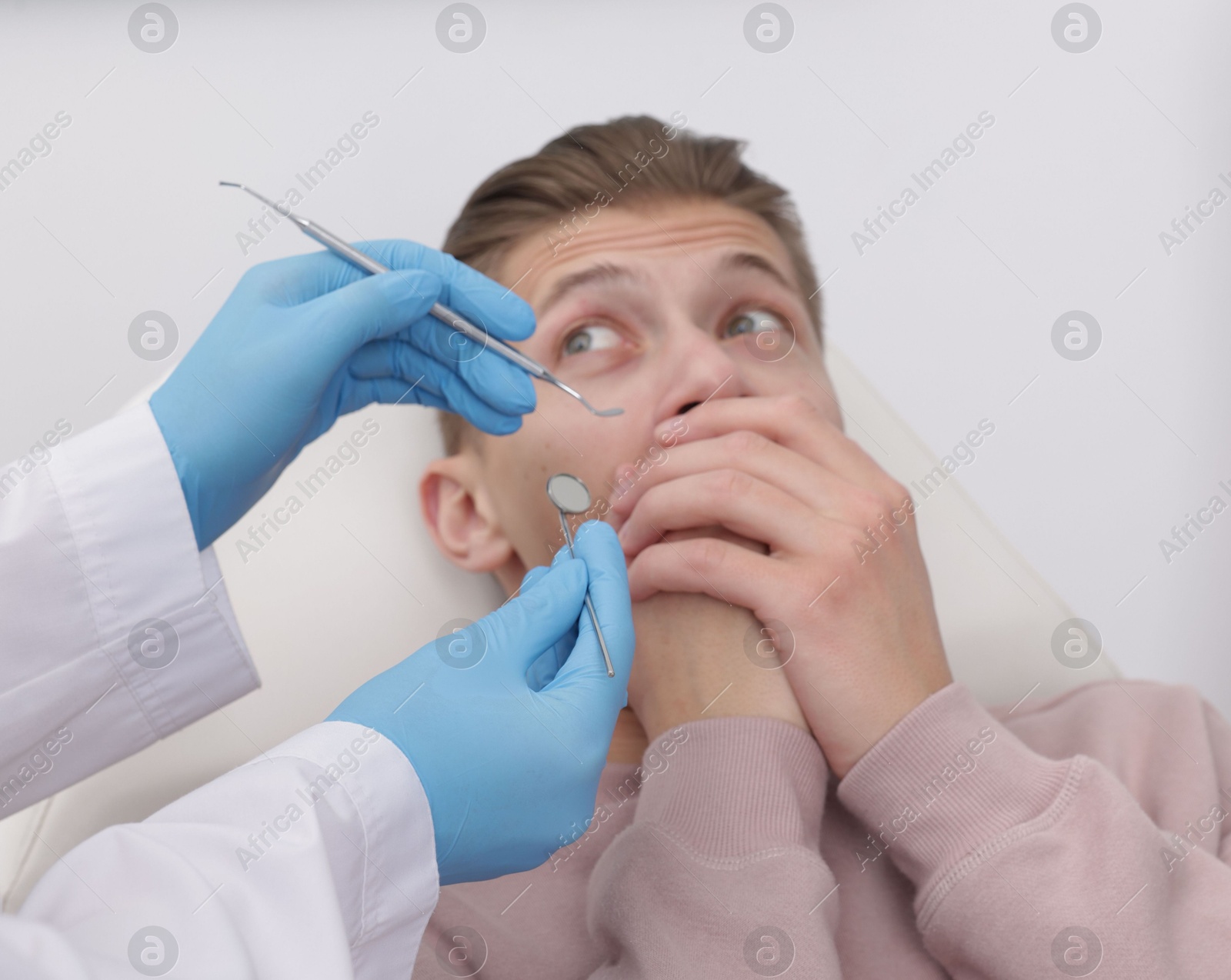 Photo of Scared man covering mouth and dentist with tools on grey background