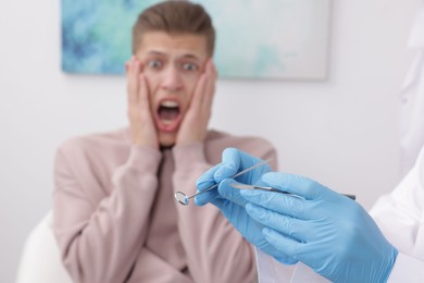 Scared man having appointment with dentist in clinic, selective focus