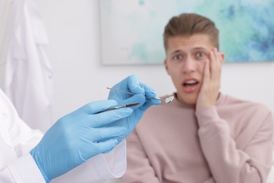 Scared man having appointment with dentist in clinic, selective focus