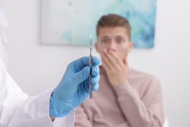 Scared man having appointment with dentist in clinic, selective focus