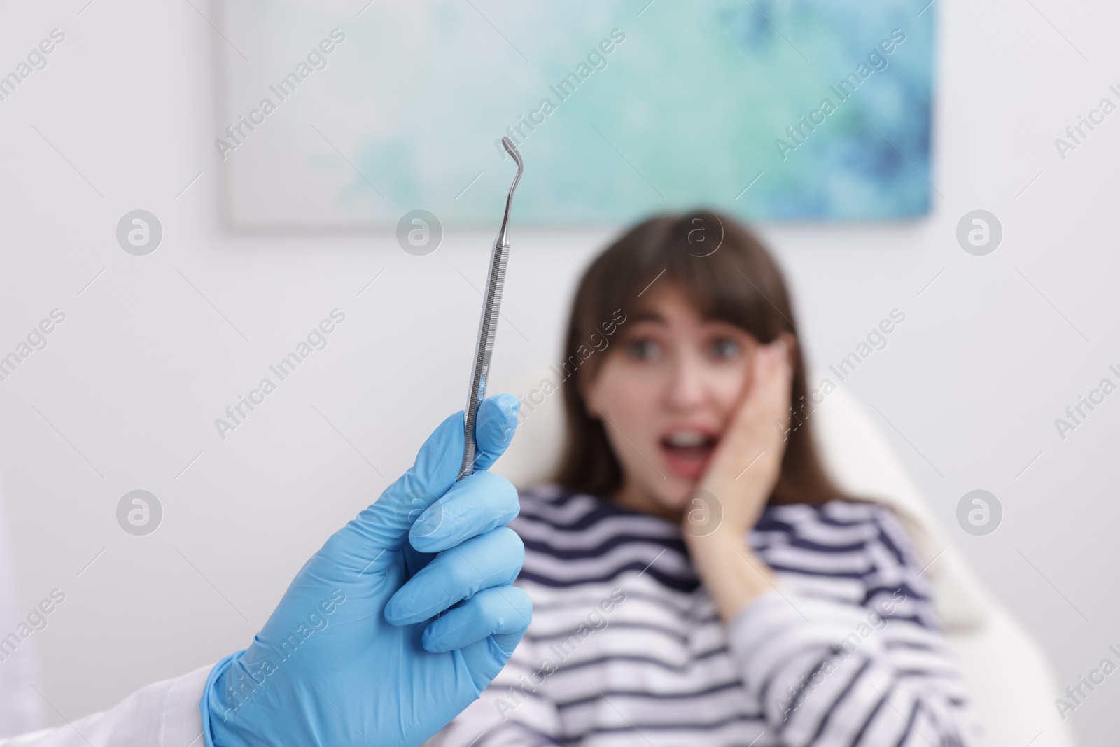 Photo of Scared woman having appointment with dentist in clinic, selective focus