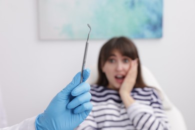 Scared woman having appointment with dentist in clinic, selective focus