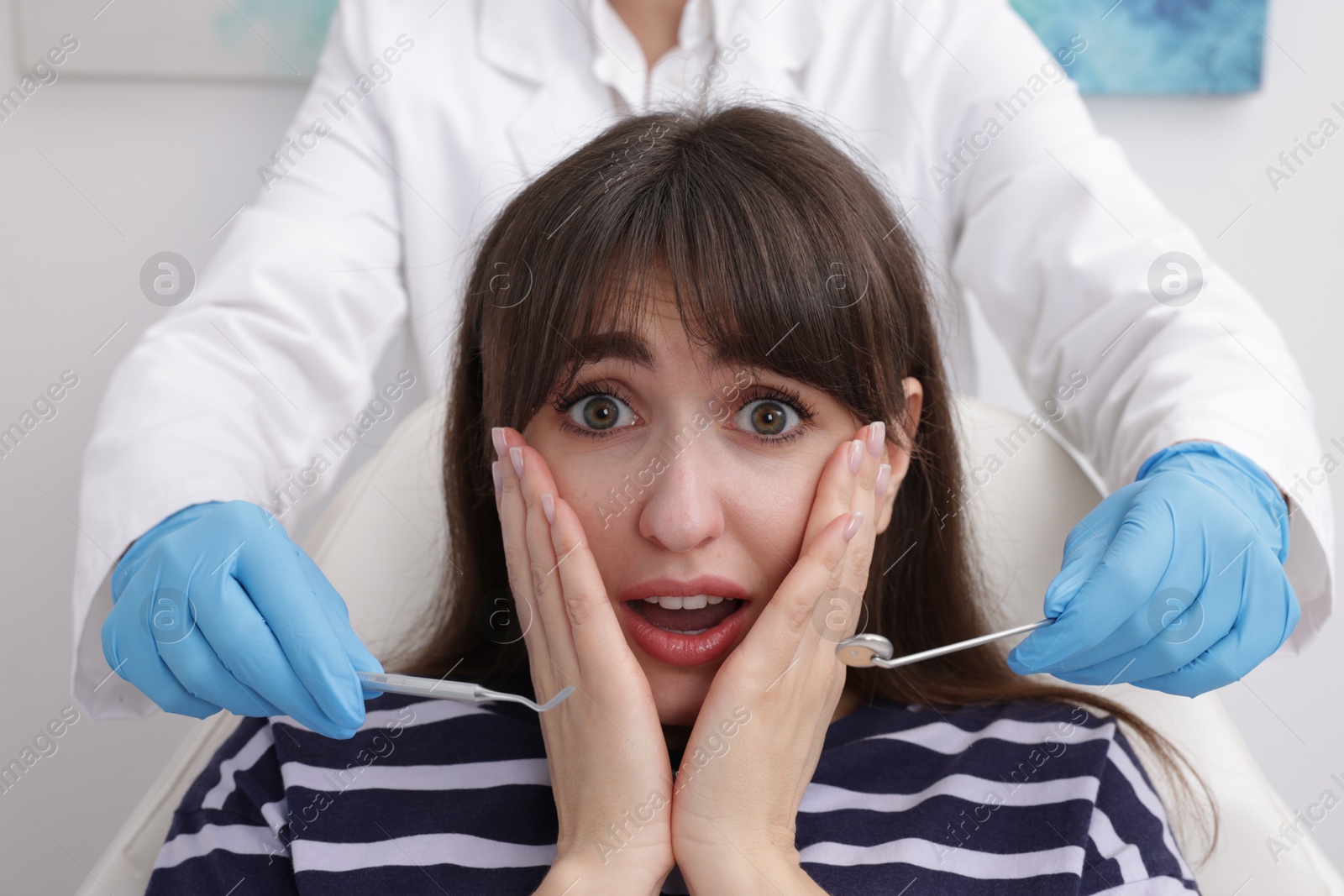 Photo of Scared woman having appointment with dentist in clinic