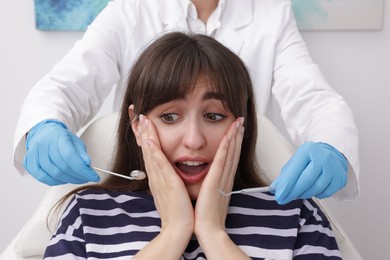 Photo of Scared woman having appointment with dentist in clinic