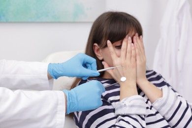 Scared woman covering face and dentist with tools in clinic