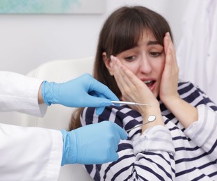 Photo of Scared woman having appointment with dentist in clinic