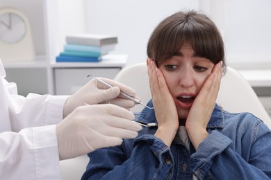 Photo of Scared woman having appointment with dentist in clinic