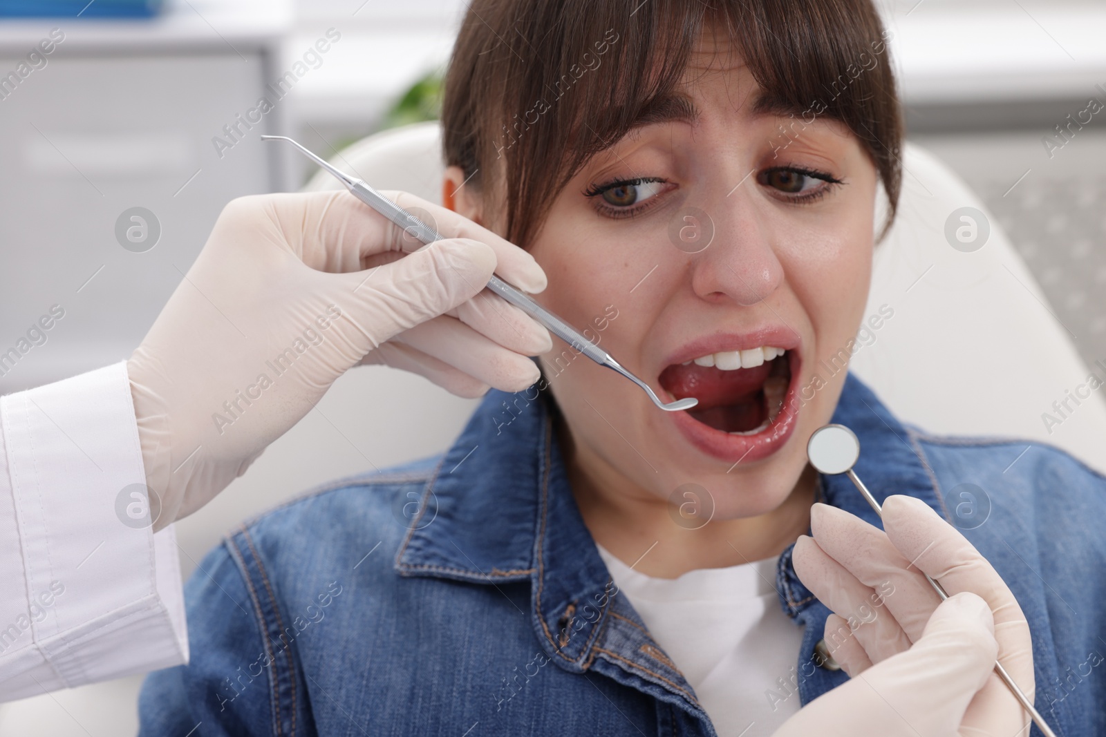 Photo of Scared woman having appointment with dentist in clinic