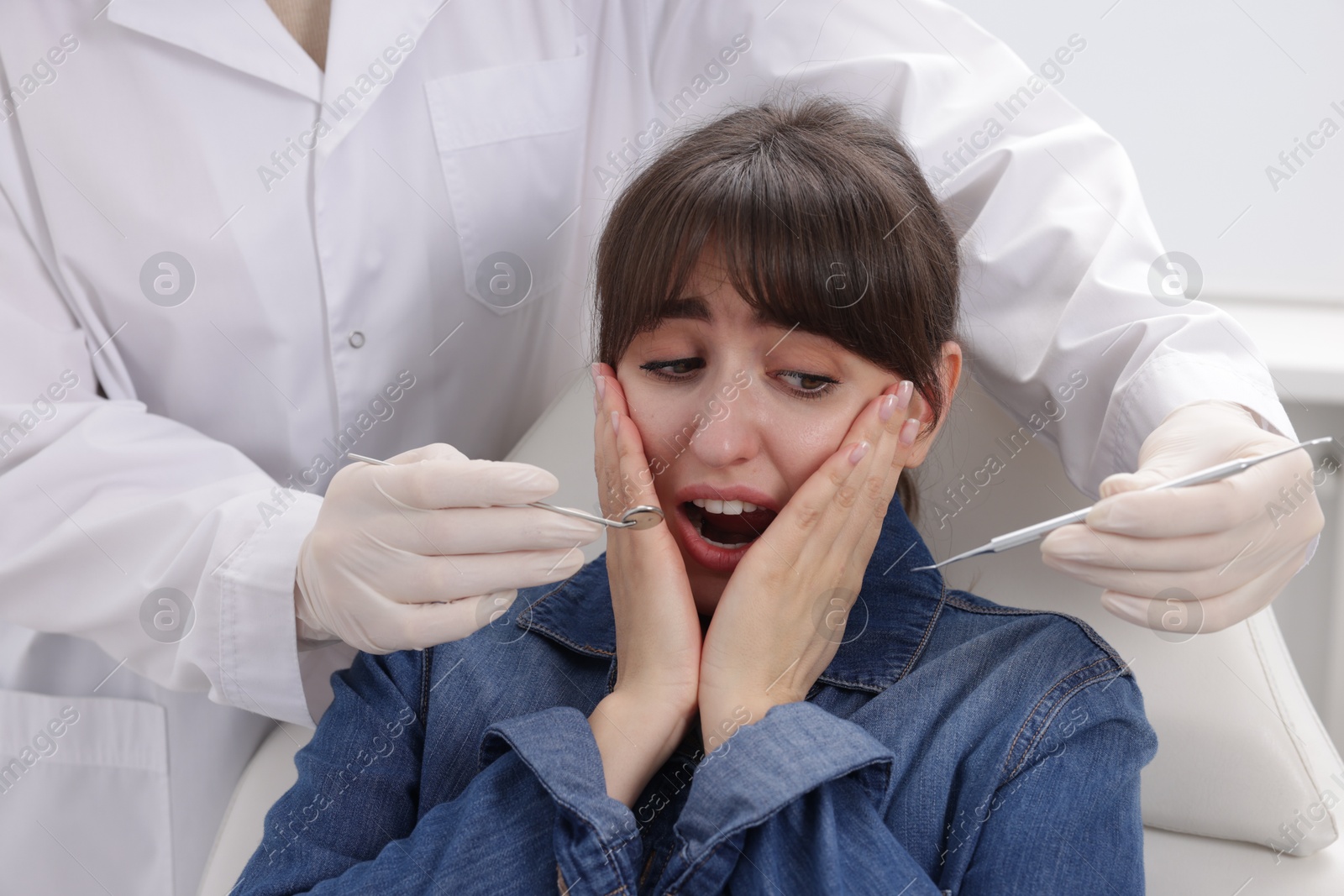 Photo of Scared woman having appointment with dentist in clinic