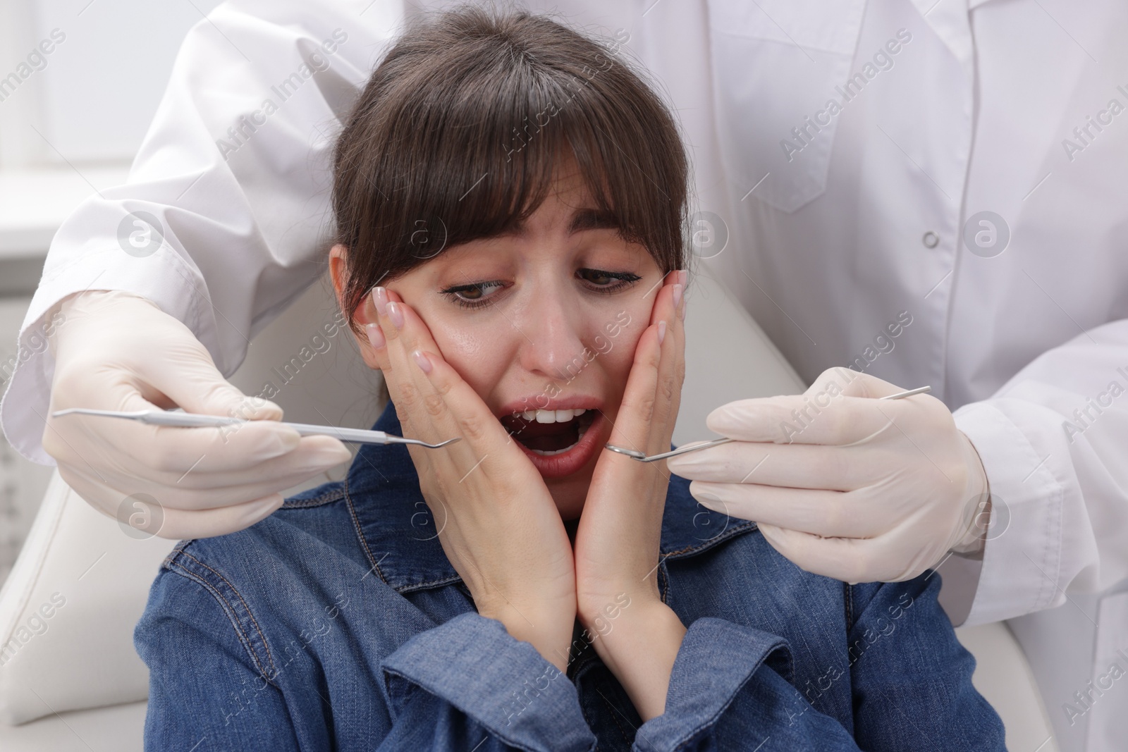 Photo of Scared woman having appointment with dentist in clinic