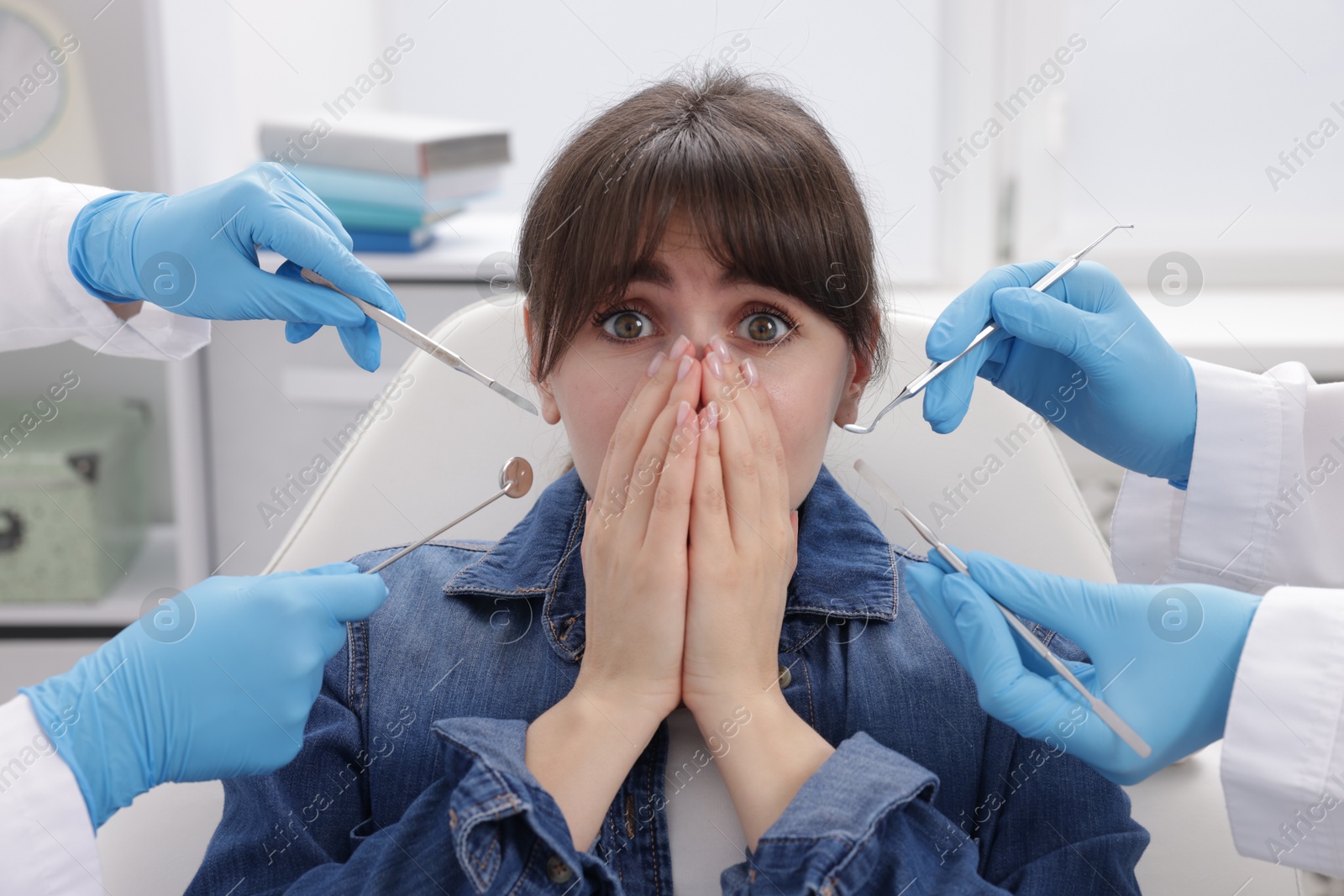 Photo of Scared woman having appointment with dentist and assistant in clinic