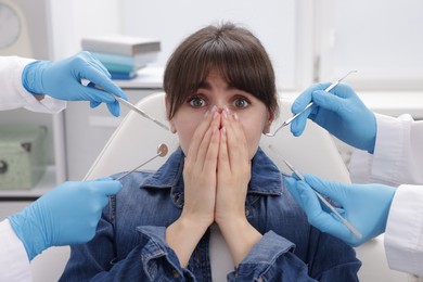 Scared woman having appointment with dentist and assistant in clinic