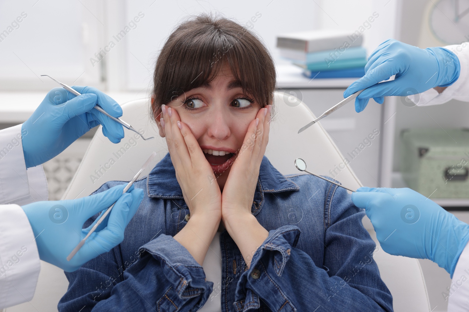 Photo of Scared woman having appointment with dentist and assistant in clinic