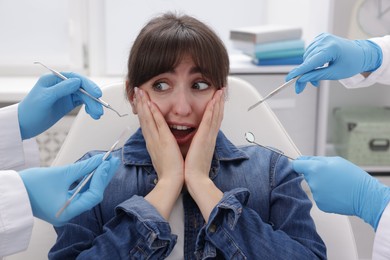 Scared woman having appointment with dentist and assistant in clinic