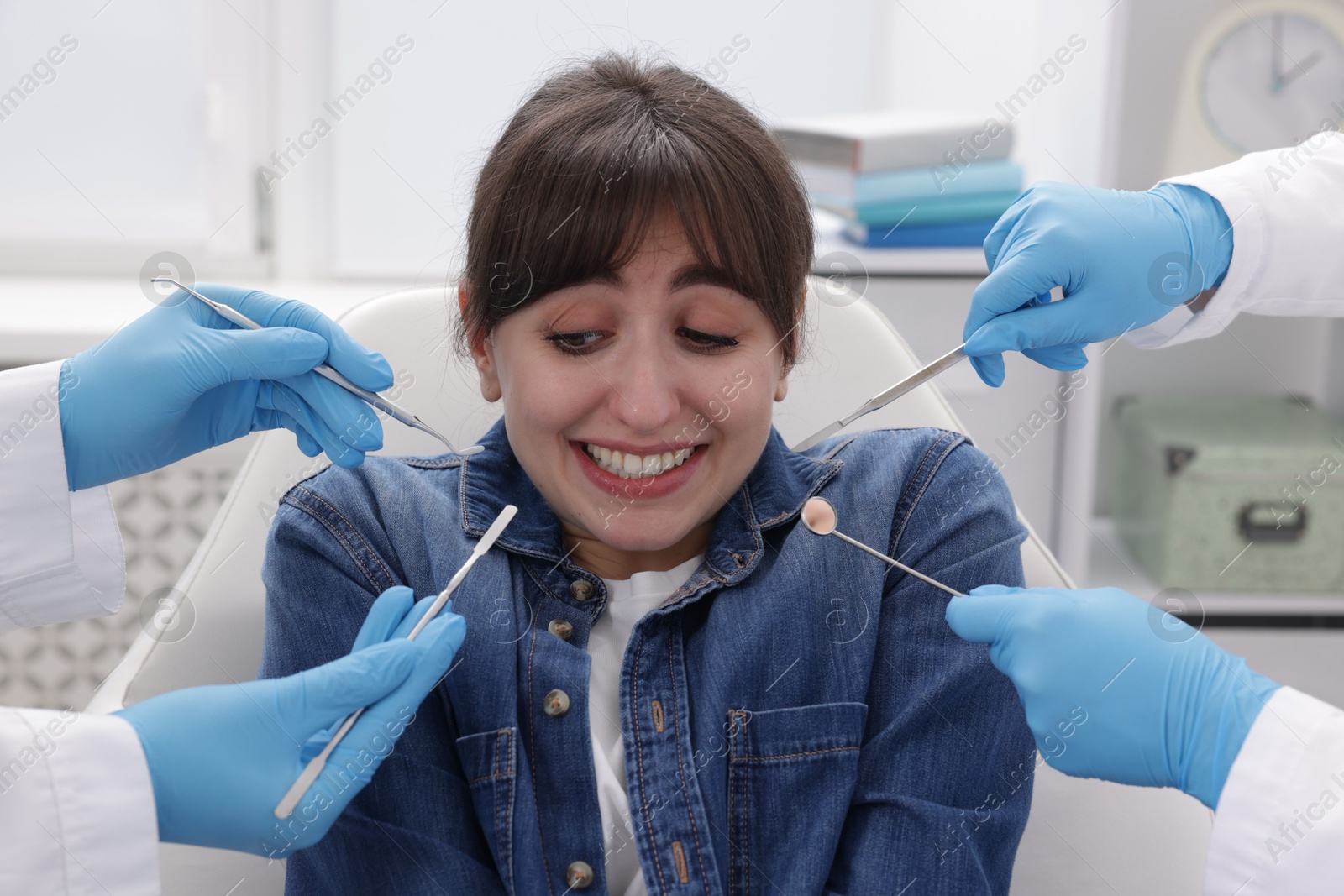 Photo of Scared woman having appointment with dentist and assistant in clinic