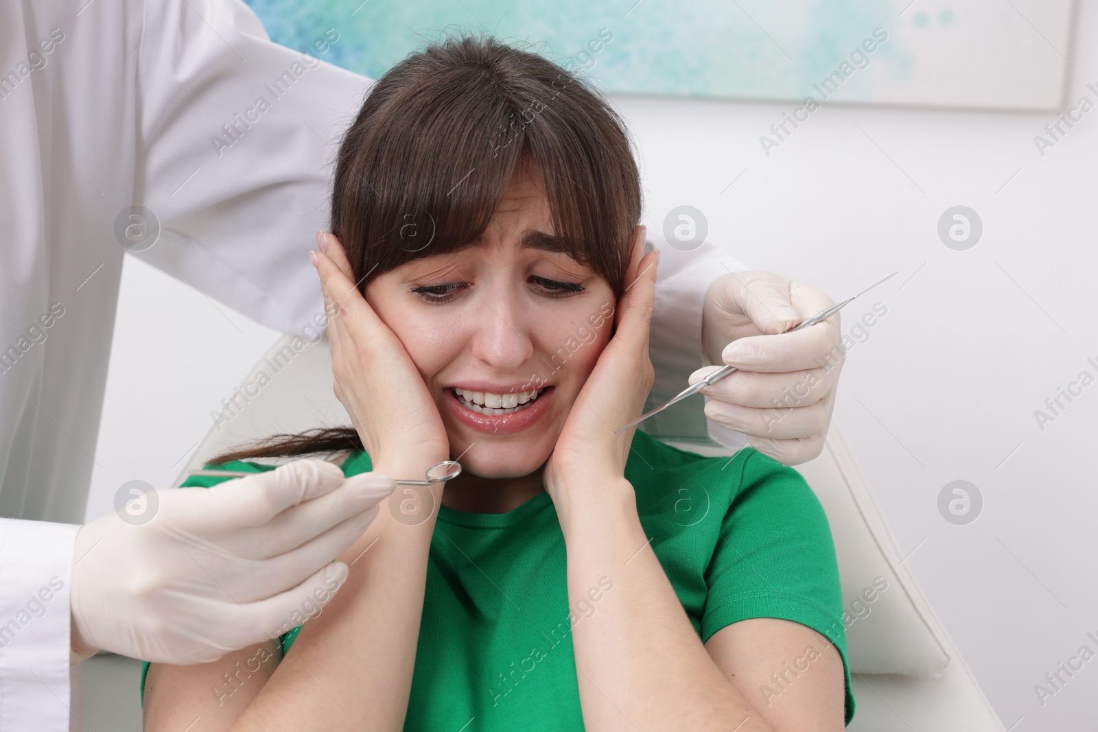 Photo of Scared woman having appointment with dentist in clinic