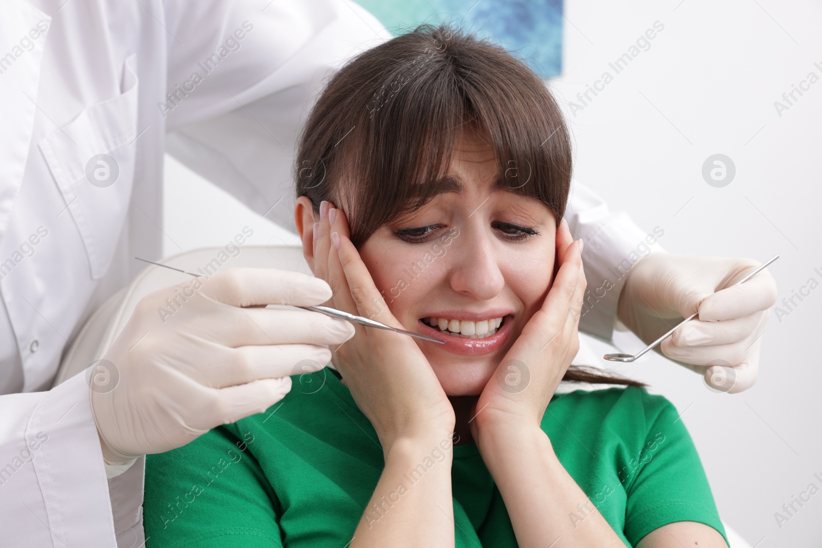 Photo of Scared woman having appointment with dentist in clinic