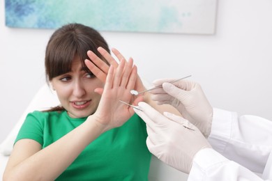 Photo of Scared woman refusing dentist's examining in clinic