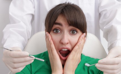 Photo of Scared woman having appointment with dentist on grey background