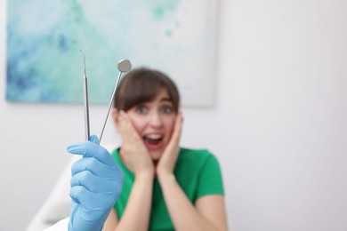 Photo of Scared woman having appointment with dentist in clinic, selective focus. Space for text