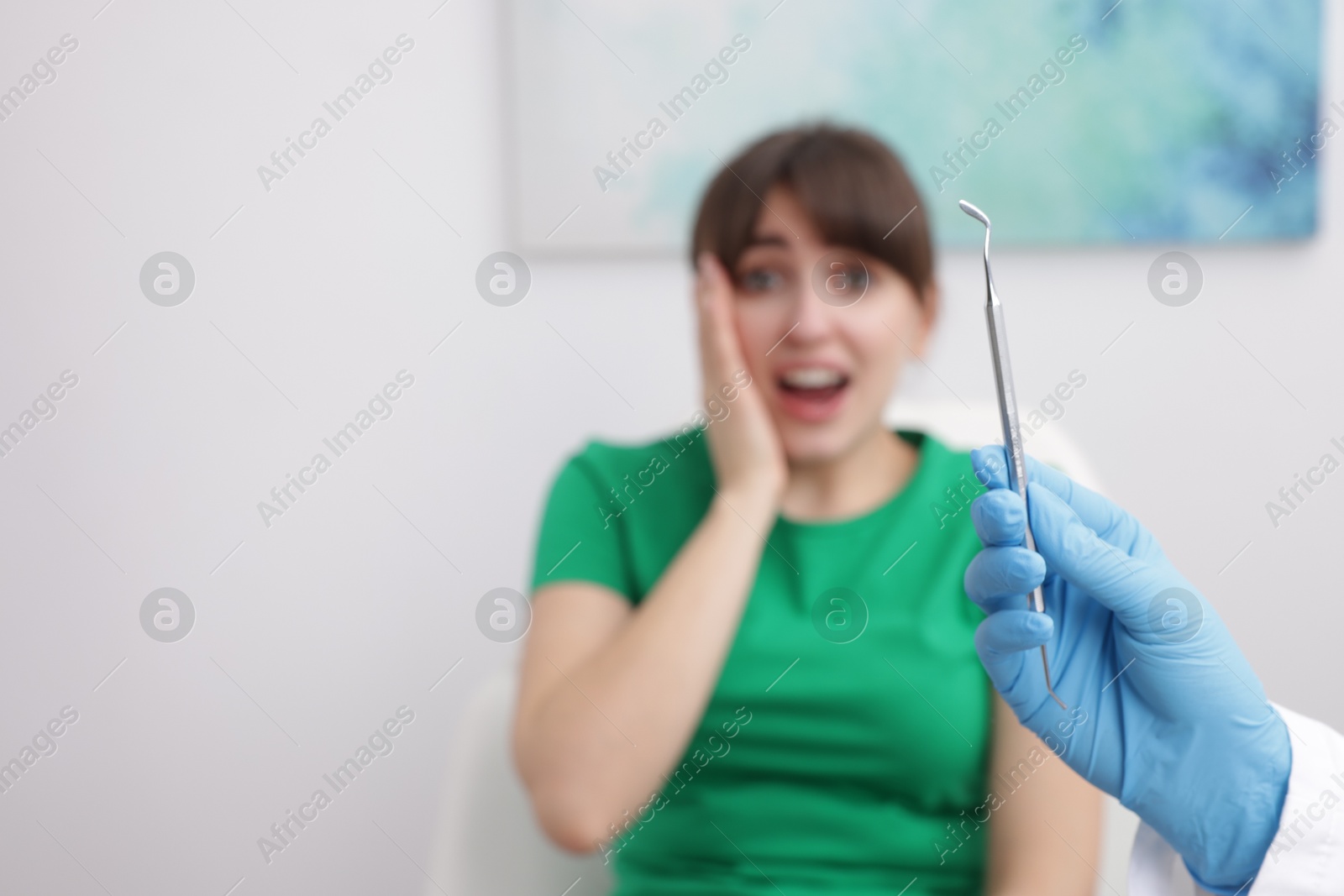 Photo of Scared woman having appointment with dentist in clinic, selective focus. Space for text