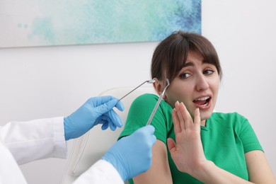 Photo of Scared woman refusing dentist's examining in clinic